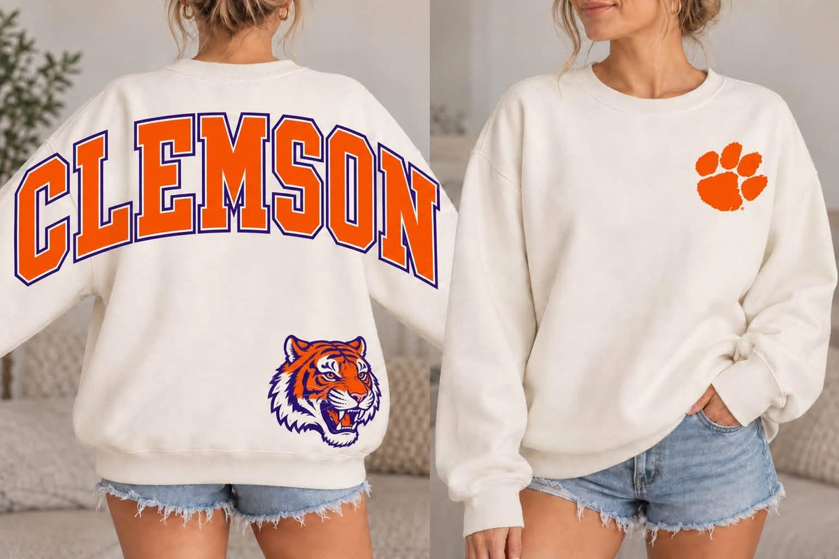 Cream Clemson Tigers sweatshirt with orange varsity Clemson back lettering outlined in purple, tiger head, and orange paw print on the left chest