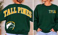 Forest green Tall Pines sweatshirt showing gold full-back varsity lettering, white wolf emblem, and patterned green and gold left-chest initials